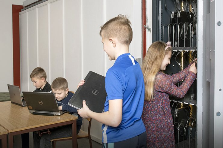 børn der tager computere ud af et pc-skab på en skole